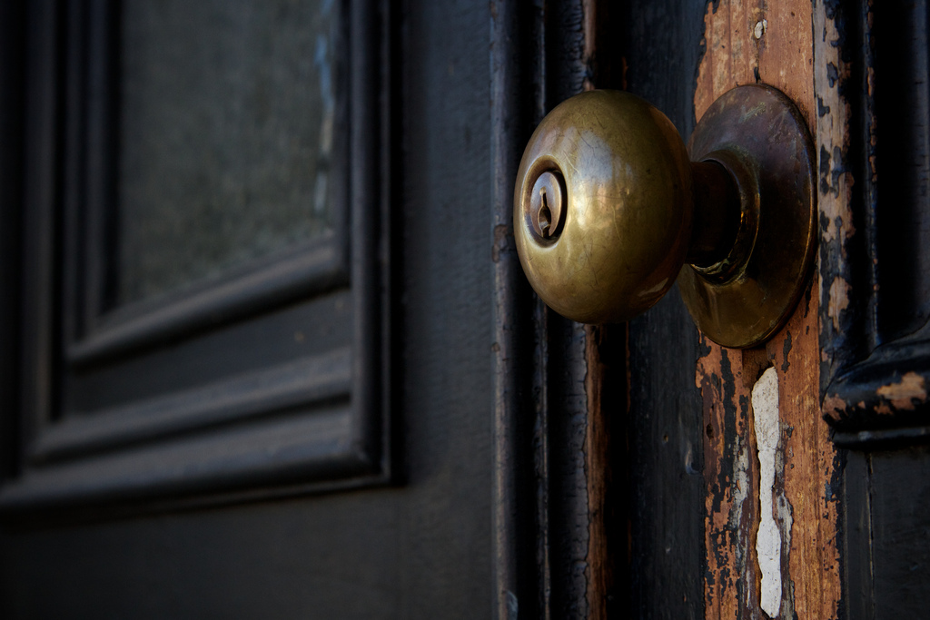 A picture of a dark brown door with a golden door knob