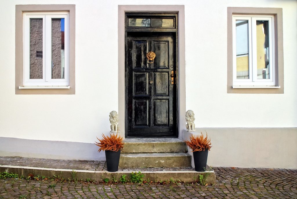 photograph of black front door with steps and plant pots
