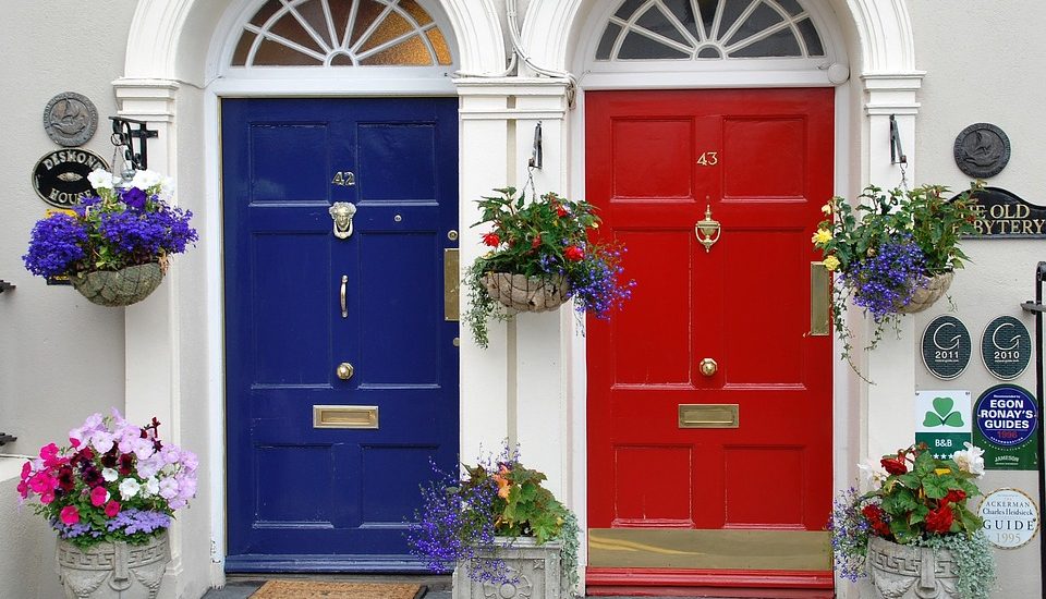 photograph of a blue front door and a red front door with hanging baskets