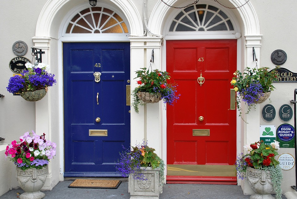 photograph of a blue front door and a red front door with hanging baskets