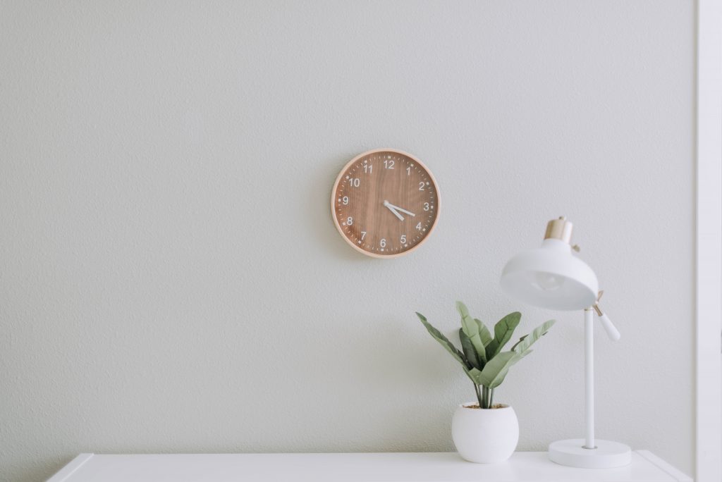 Minimalist white desk with lamp, plant and wall clock