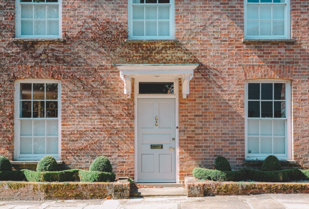 Photograph of a red brick Georgian-style house with a pale green front door