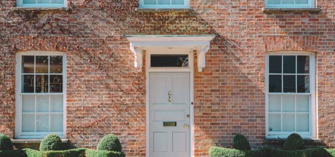 Photograph of a red brick Georgian-style house with a pale green front door