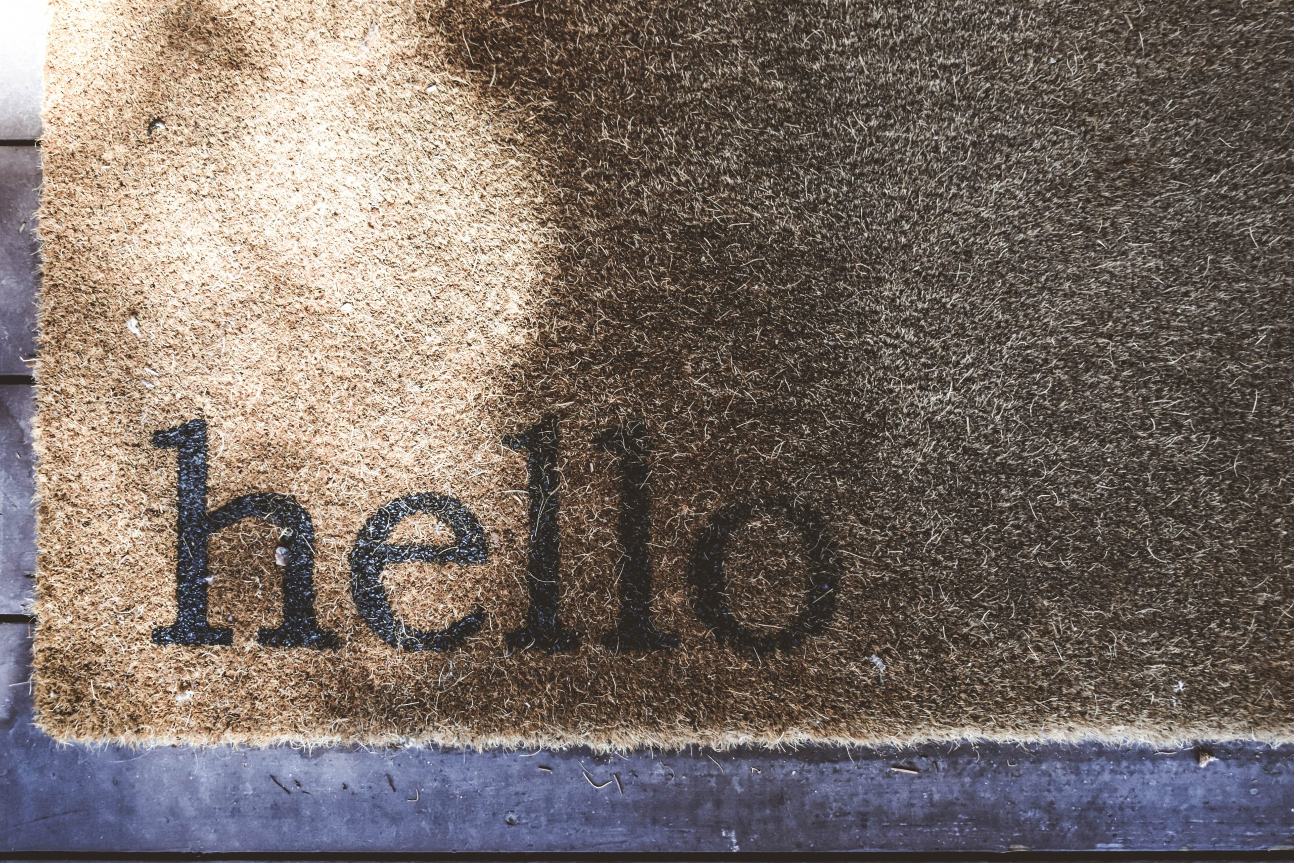Photograph of a welcome mat with "hello" printed on the bottom left corner