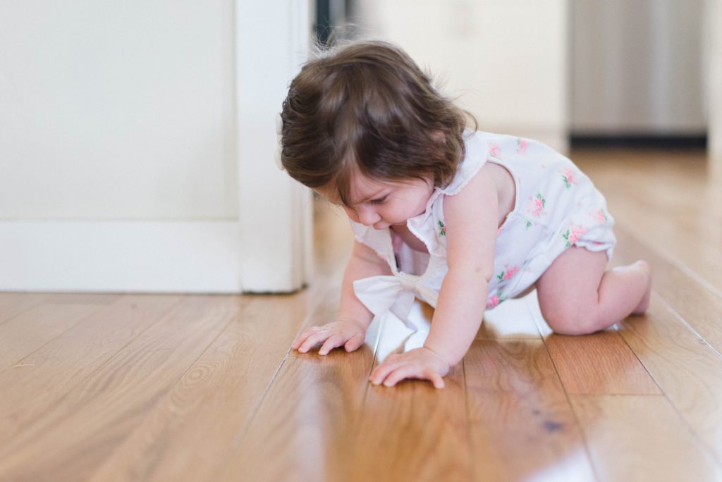 Photo of a baby girl crawling on a wooden floor
