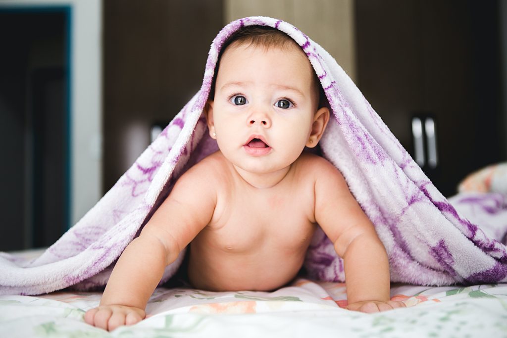 Photo of a baby peeping out from under a pink blanket