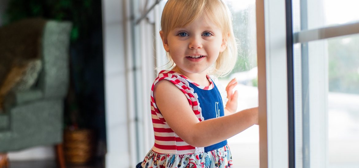 Photo of toddler girl standing by a glass door