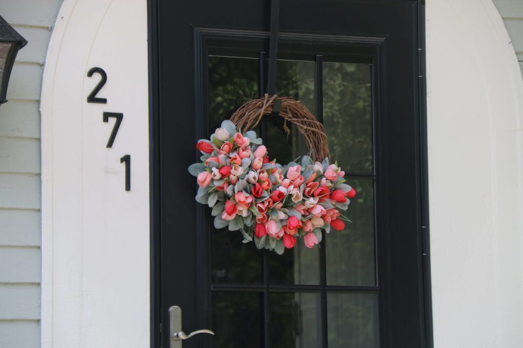 Black door with multiple glazed panels with floral wreath hanging on it