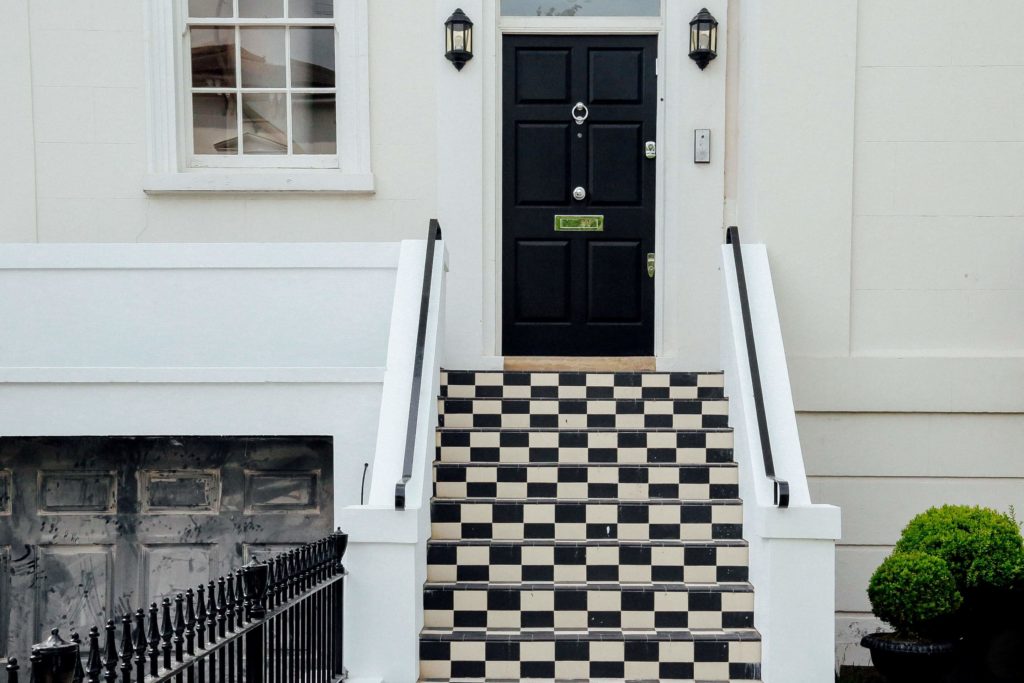 Black traditional style front door on a townhouse with black & white steps