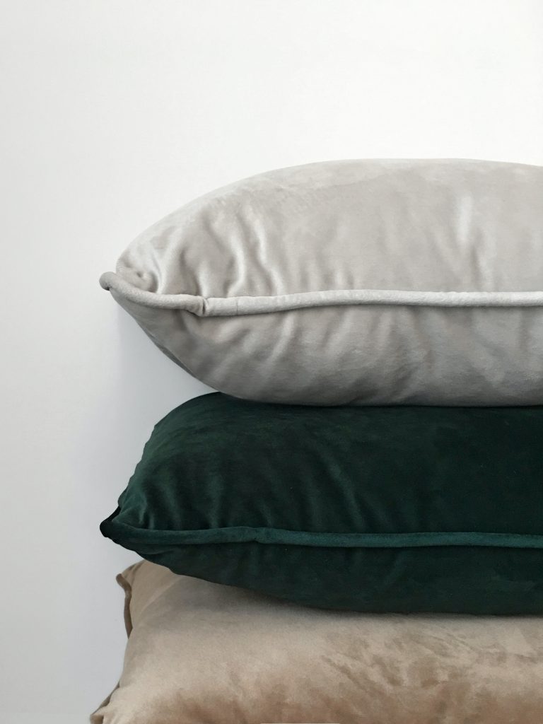Soft velvet cushions in 1930s colours such as dark green and dusky neutrals