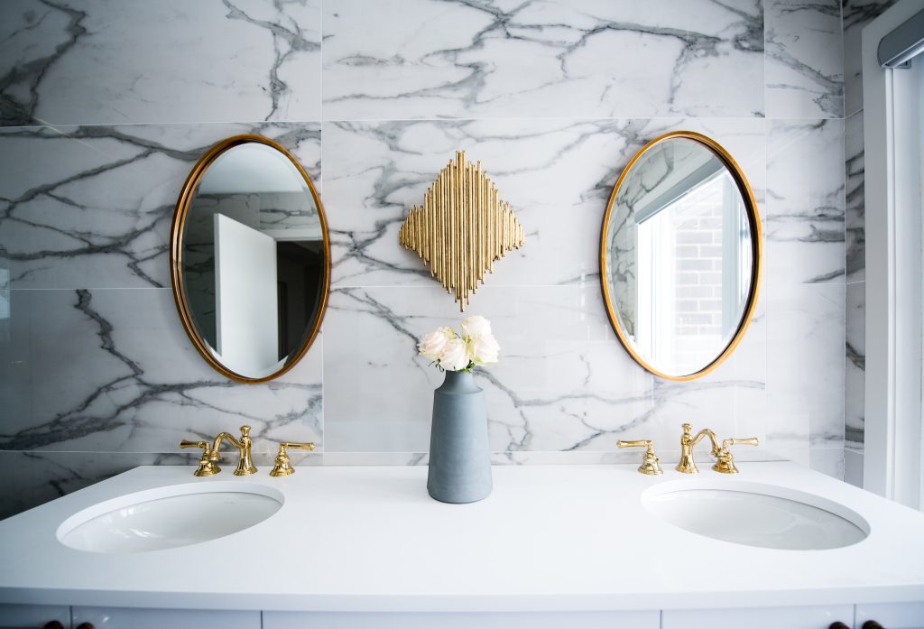 Marble bathroom with gold mirrors and twin sinks