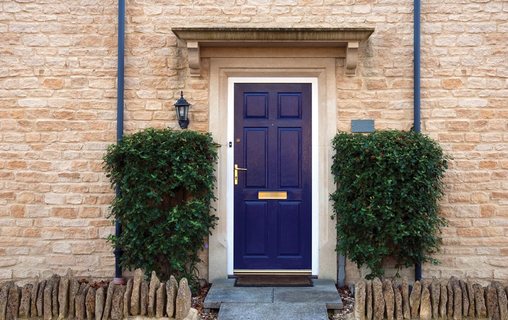 Blue front door surrounded by shrubs