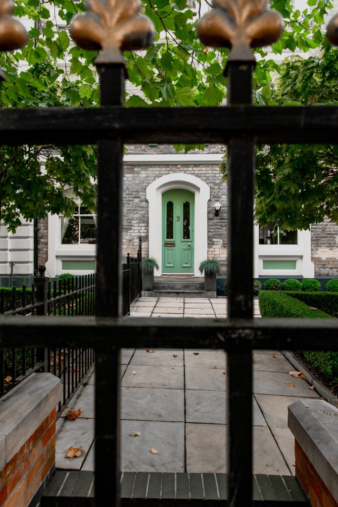 Green front door behind an iron gate